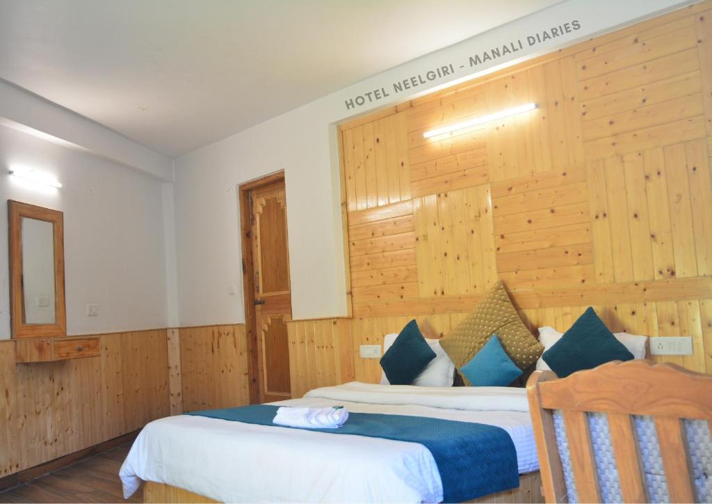 马拉里Hotel Neelgiri - Manali Diaries的酒店客房设有两张床,墙上有标志