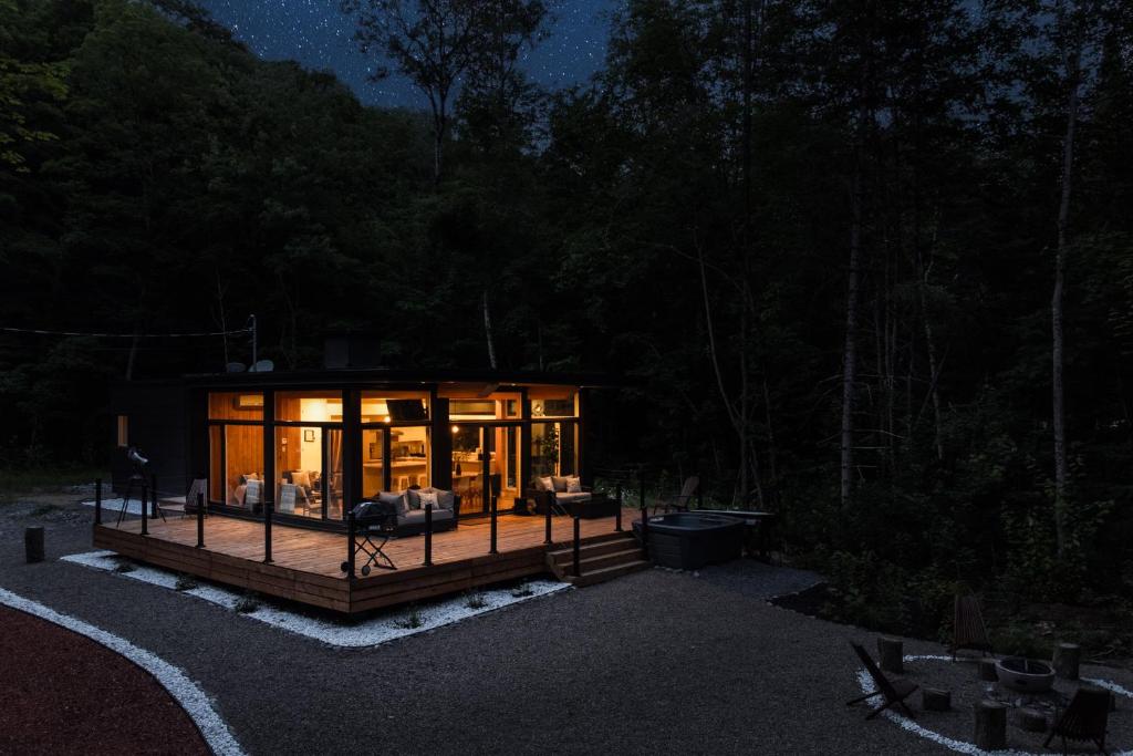Saint-Rémi-dʼAmherstStarry Tremblant l Design Glass View Cabin Spa Lake的夜晚在树林里的一个小屋