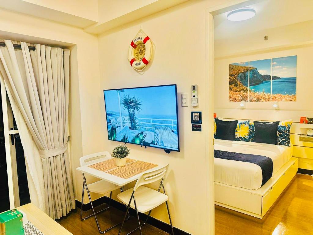马尼拉CELANDINE Residence by DMCI的一间卧室配有一张床、一张书桌和一台电视。