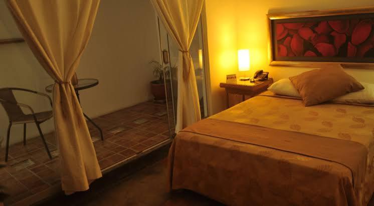 皮乌拉Hotel Mango Verde Bed & Breakfast的卧室配有1张床、1张桌子和1把椅子