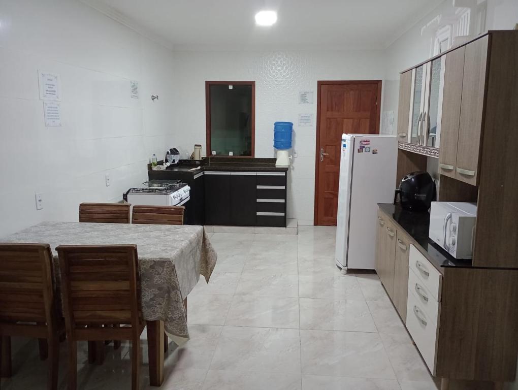 皮乌马Casa Temporada Monte H Piuma.的厨房配有桌子和白色冰箱。