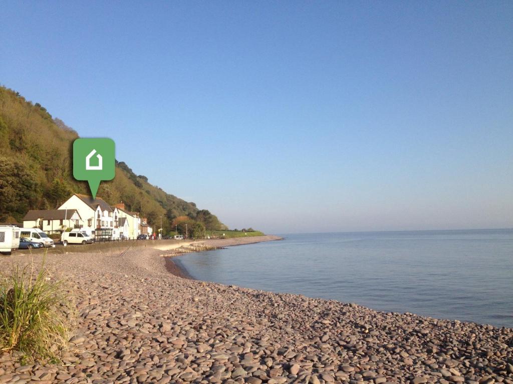 曼海德2 Bed in Minehead 75338的海滩上有一个绿色的标志,位于水边