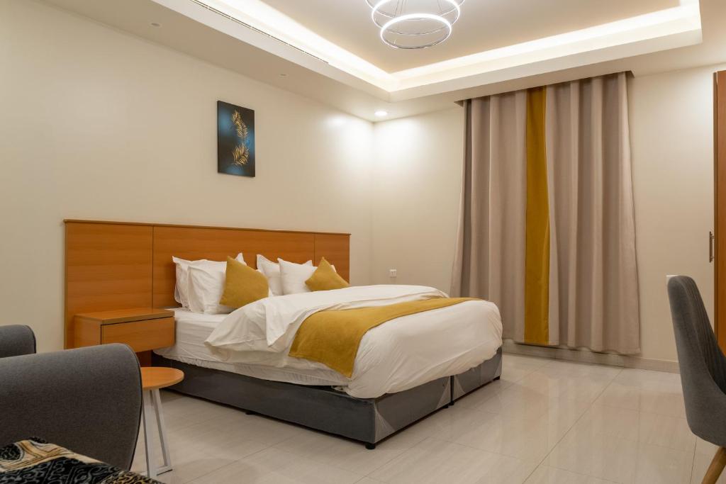 利雅德Al Nakheel Park Serviced Apartment的一间卧室配有一张带白色和黄色枕头的大床