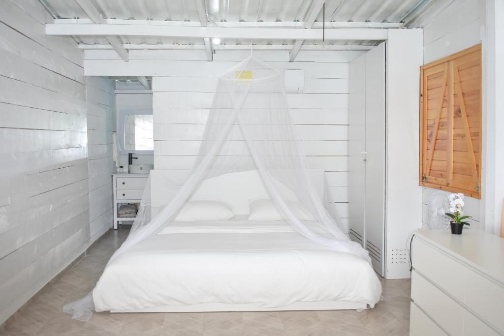 Ocumare de la CostaAqua Vista La Ciénaga的白色卧室配有带蚊帐的床