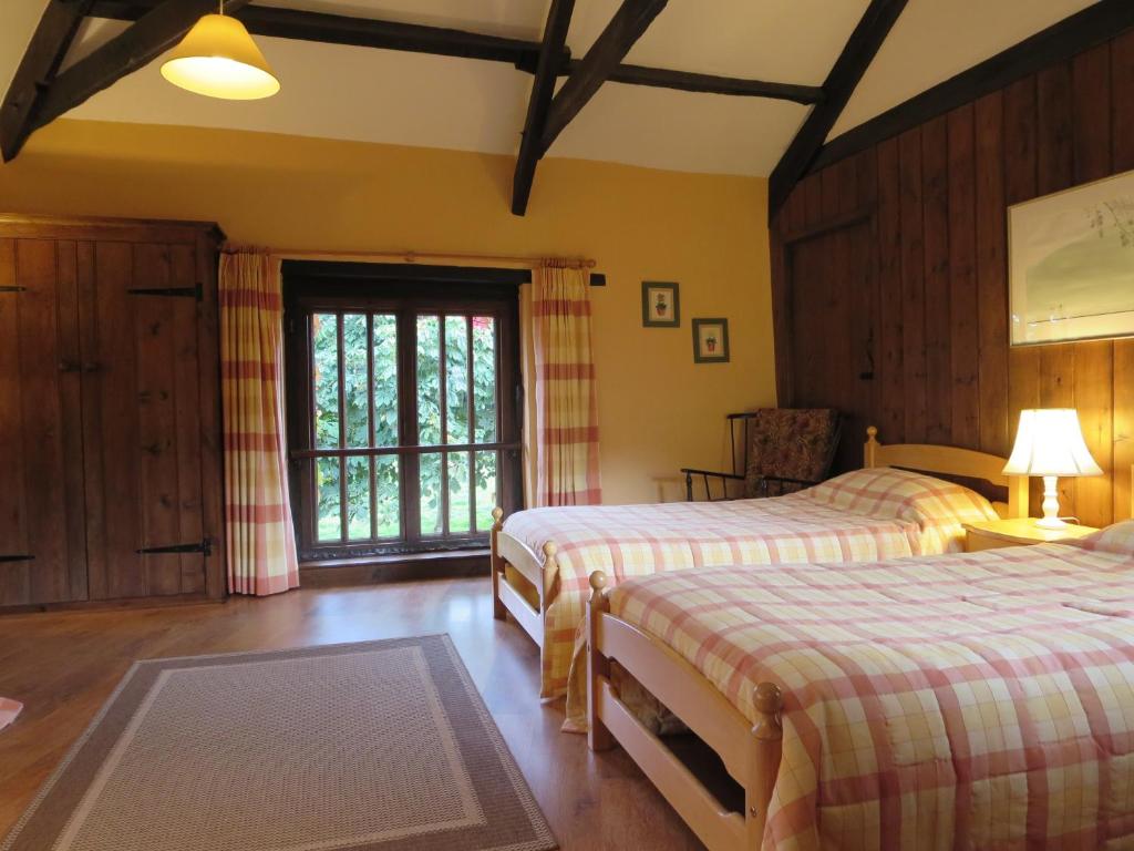 克雷迪顿Combe Lancey Farmhouse B&B的一间卧室设有两张床和窗户。
