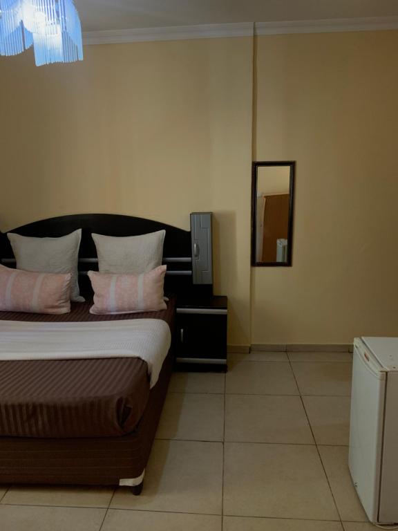 卢萨卡SUPERSTONE LODGE的一间卧室配有一张带粉红色枕头和镜子的床