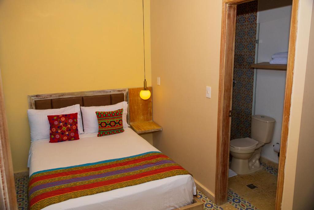 卡塔赫纳Coco Beach Hotel - Rooftop & Beach Club的小卧室配有带色彩缤纷枕头的床