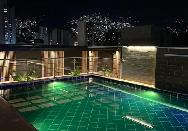 麦德林Hotel California Center的一座晚上在大楼里带灯光的游泳池