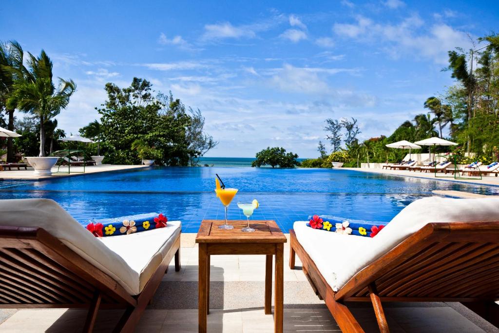 美奈维多利亚潘切海滩Spa度假酒店的一个带两把椅子和一张桌子的度假村游泳池