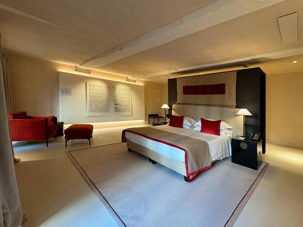热那亚Hotel Palazzo Durazzo Suites的一间卧室配有一张大床和一张红色椅子
