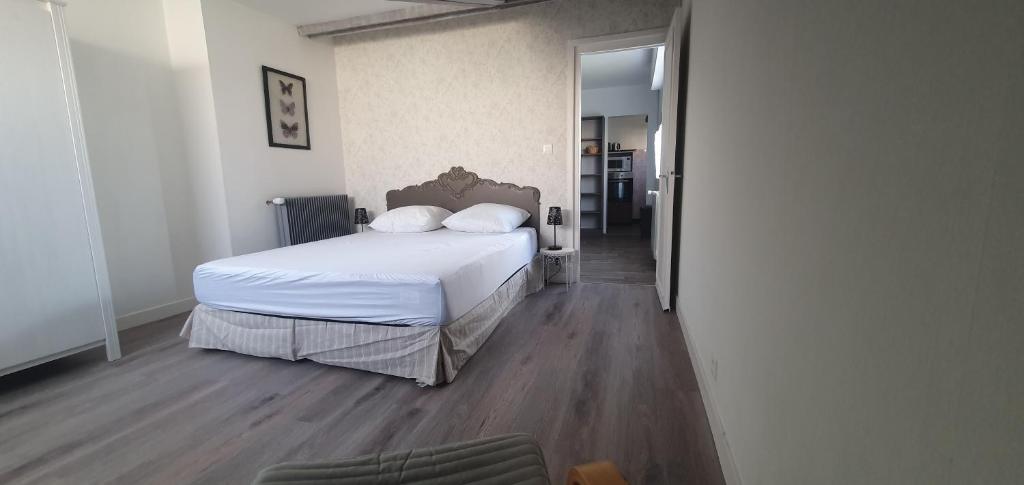 达克斯Villa Argentine T2 classé 2* thème cosy的一间卧室配有一张铺有木地板的白色床单。