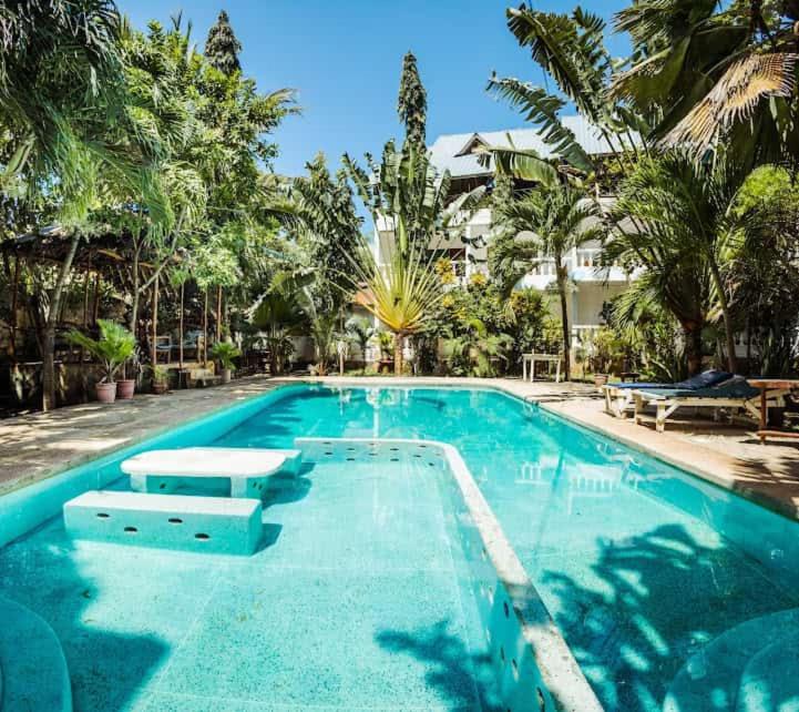 迪亚尼海滩Hildas Studio的一座拥有蓝色海水和棕榈树的大型游泳池