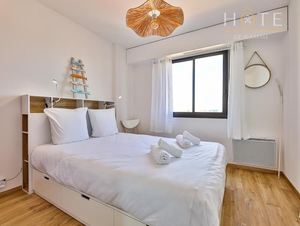 莱萨布勒-多洛讷Appartement au pied de la plage, vue imprenable sur la mer的白色卧室配有带毛巾的大型白色床
