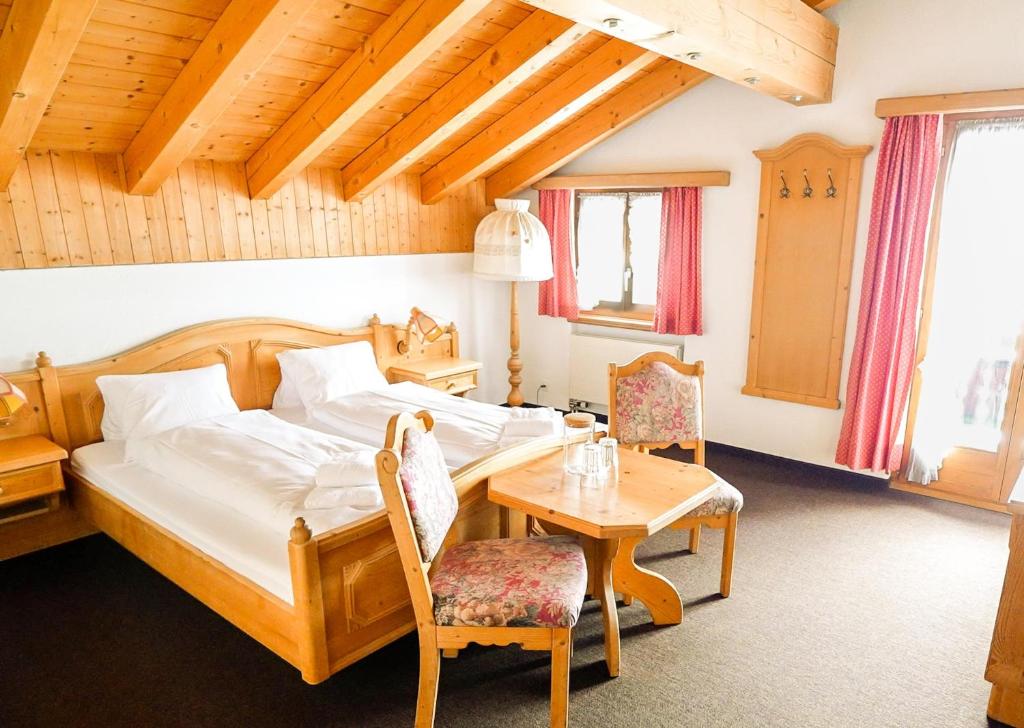塞德龙Hotel Postigliun Sedrun的卧室配有一张床和一张桌子及椅子