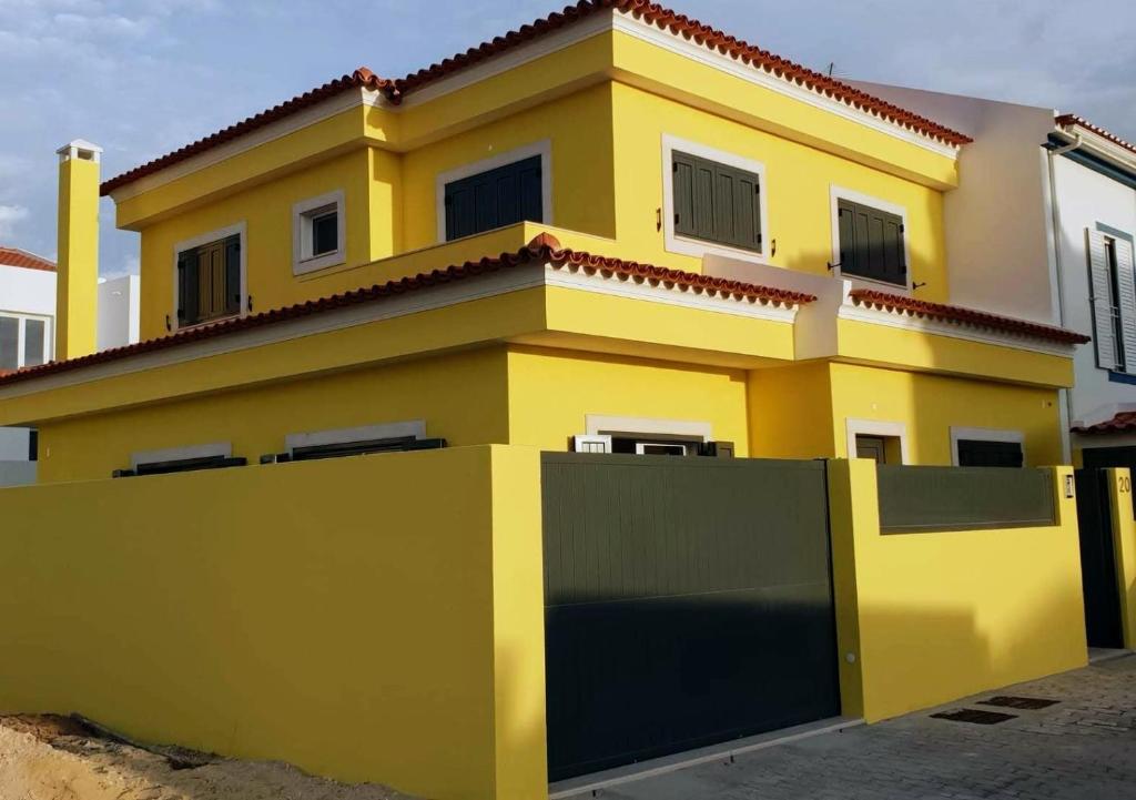 孔波尔塔Holidays Home Comporta的前面有栅栏的黄色房子