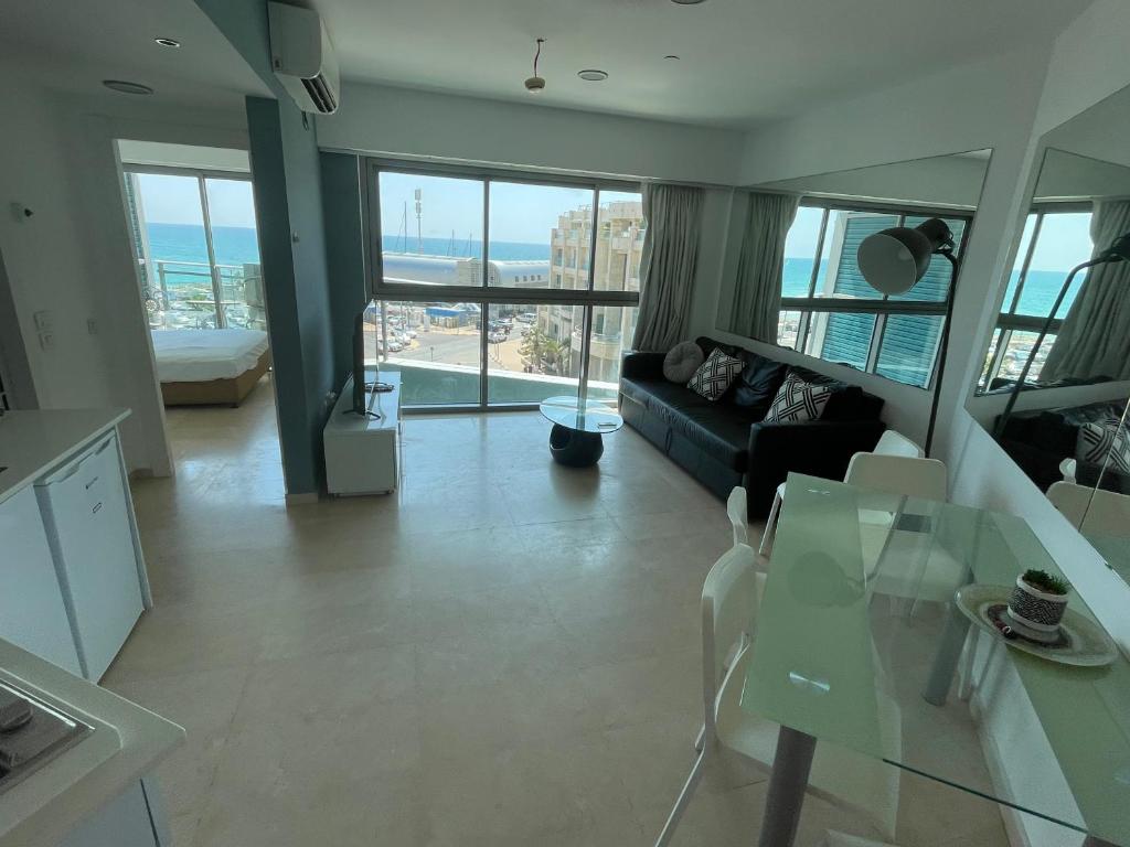 荷兹利亚Bמלון דירות אוקיינוס במרינה דירות עם נוף לים的带沙发和玻璃桌的客厅