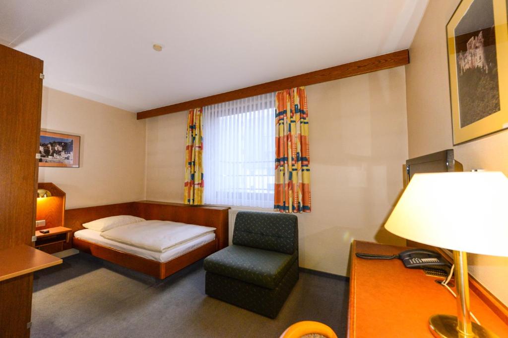 卢森堡APPART-HÔTEL MARCO POLO的客房设有床、椅子和窗户。