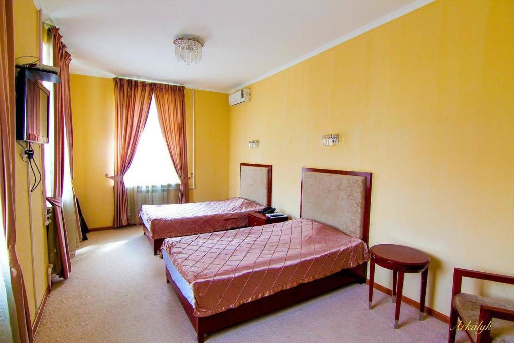 Arqalyqгостиница Аркалык的黄色墙壁客房的两张床