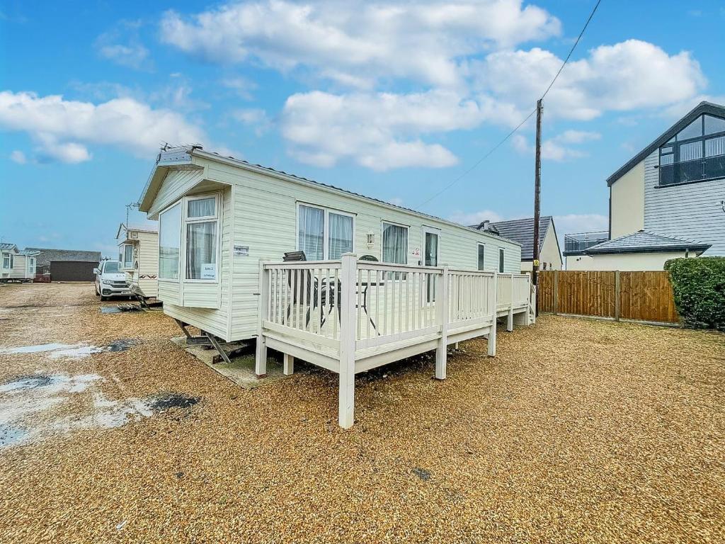 亨斯坦顿Dog Friendly 8 Berth Caravan, Minutes From The Beach In Hunstanton Ref 13003l的白色的房子,设有门廊和围栏