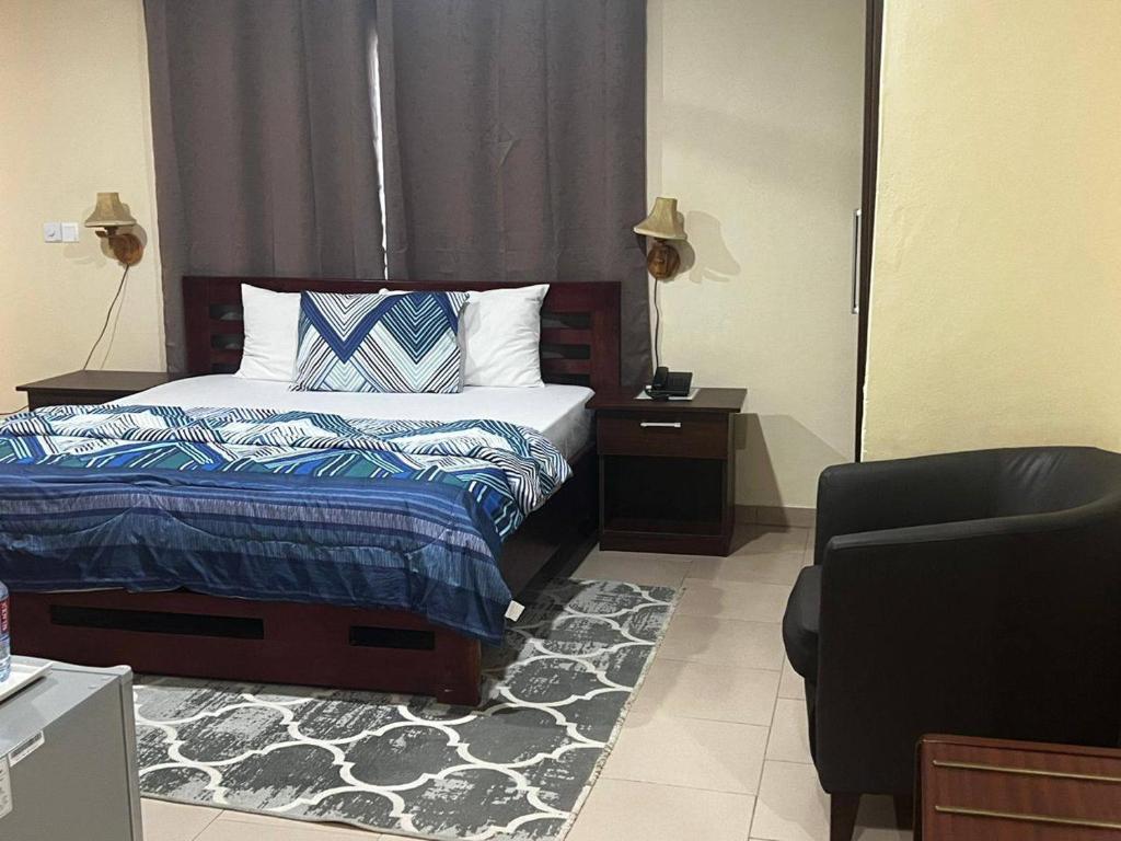 AkropongAmoaba's Inn的一间卧室配有一张床、一把椅子和镜子