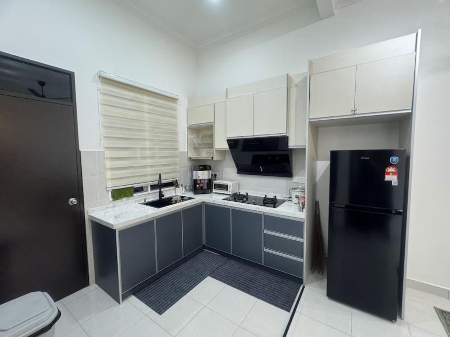 万津Hazzani Homestay KLIA的厨房配有黑冰箱和白色橱柜。