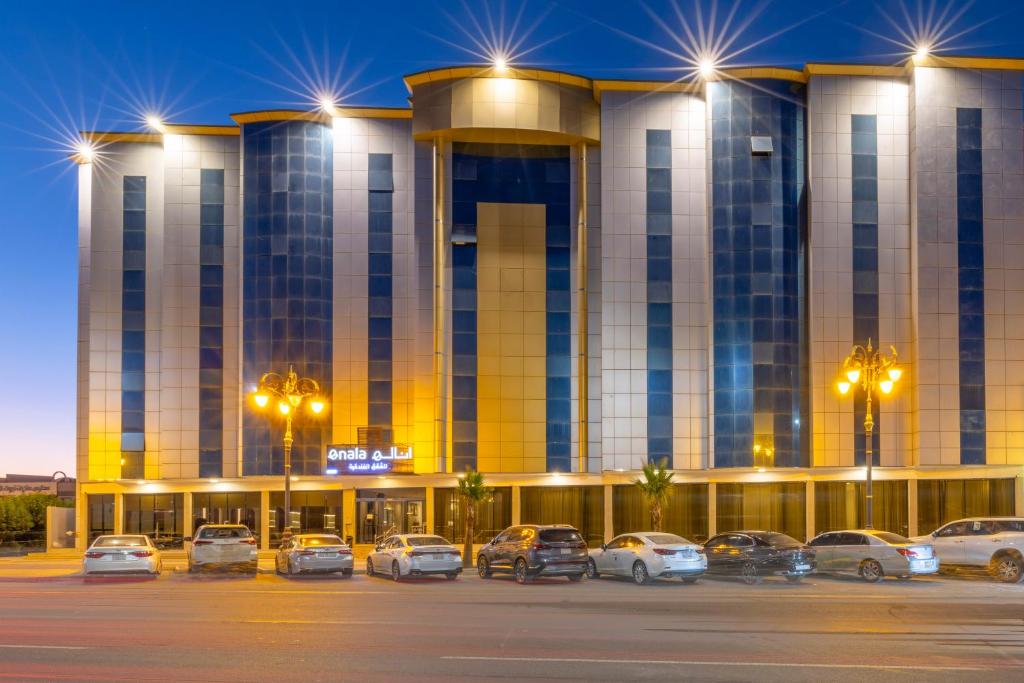 泰布克Enala Hotel - Tabuk的停车场内停放汽车的大型建筑