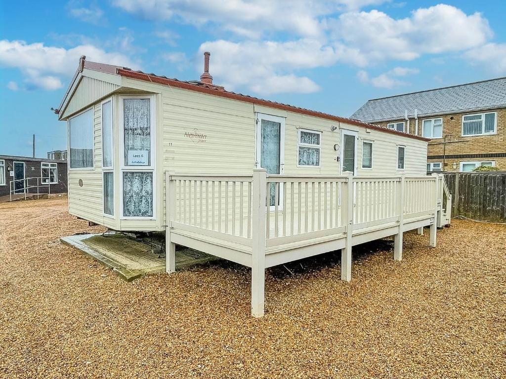 亨斯坦顿6 Berth Caravan For Hire At Lees Caravan Park In Hunstanton Ref 13006l的白色的房子,设有门廊和围栏