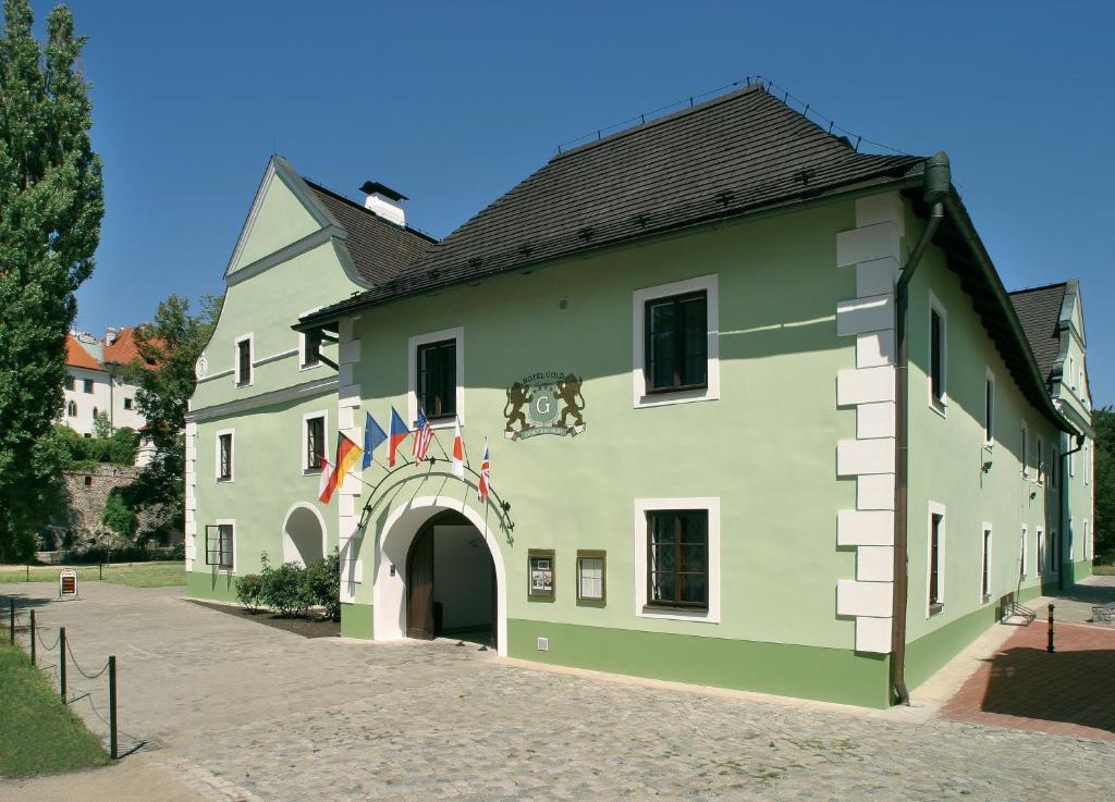 捷克克鲁姆洛夫黄金酒店的一座带拱门和旗帜的大型绿色建筑