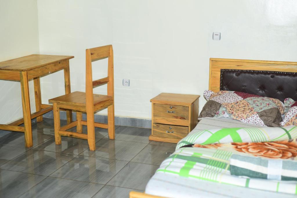 KabarondoAkagera Neighbors的一间卧室配有一张床、一张桌子和一把椅子