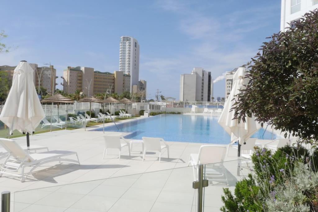 哈德拉Beach front luxury apartment - managed building的一个带白色椅子和遮阳伞的游泳池