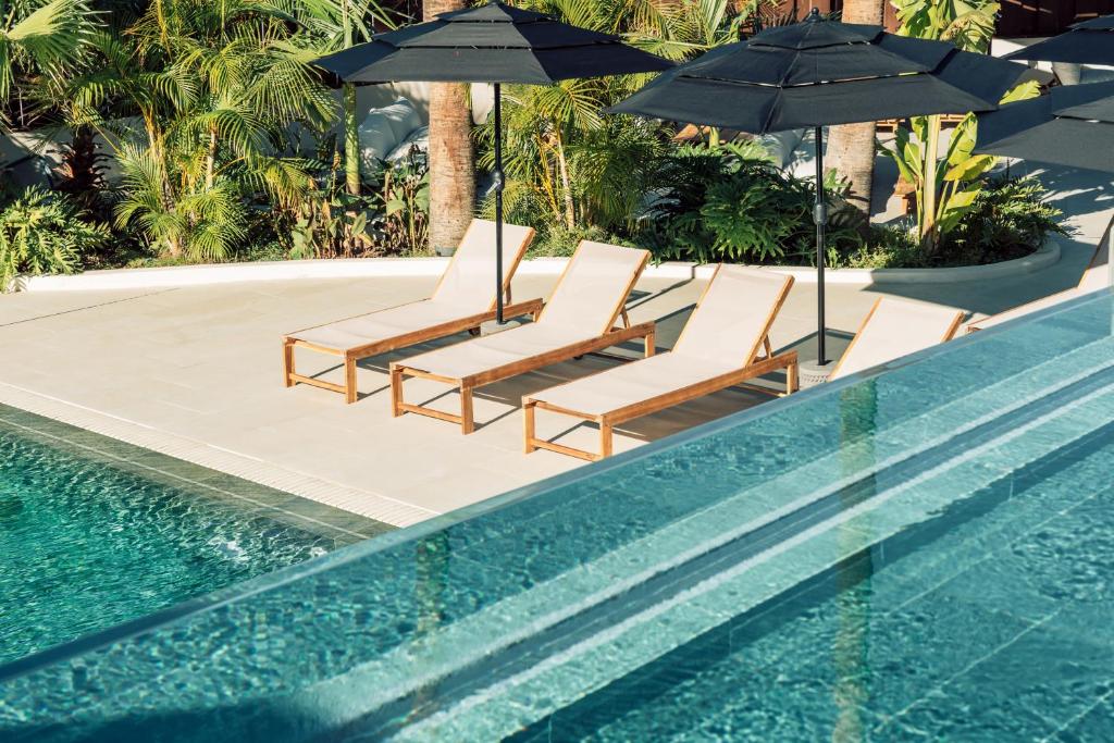 洛斯克里斯蒂亚诺斯Hotel Estefania Boutique Suites的一组椅子和遮阳伞,位于游泳池旁