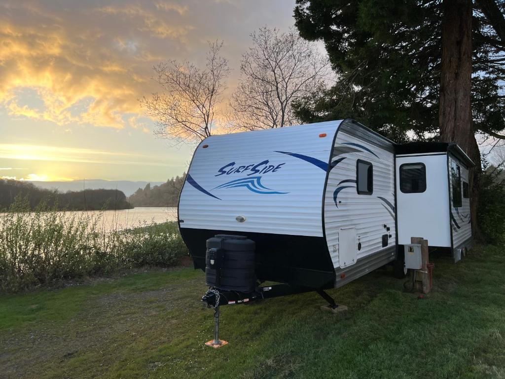 克拉马斯Surfside Glamping camper的停在湖边草地上的白色拖车