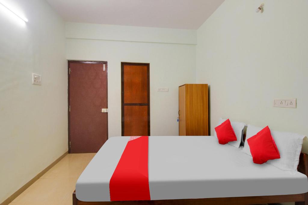 阿姆波尔Collection O Rest Inn Beach Guest House的卧室配有带红色枕头的白色床