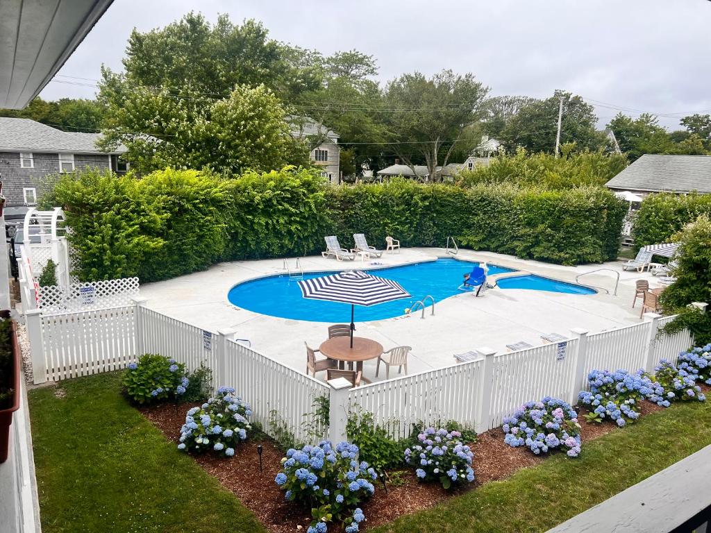 埃德加敦Edgartown Commons Vacation Apartments的游泳池周围的白色围栏,带雨伞