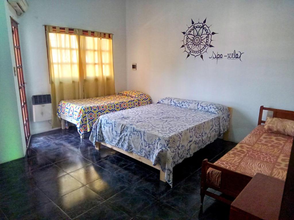 GualeguaychúHospedaje的一间设有三张床的客房,墙上有标志