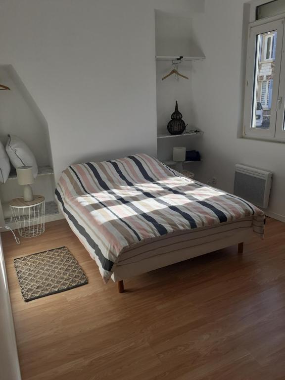 TilléMaison Natis的一间卧室配有带条纹毯子的床