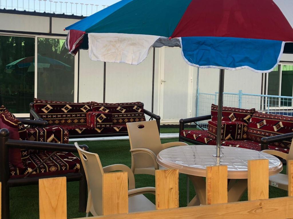 Sīdī Ḩamzahشاليه نزل أمنة的一张桌子,上面摆放着蓝色和红色的雨伞和椅子