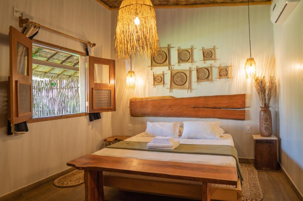 阿廷斯Rancharia Charme Beach - Pé na Areia的一间卧室配有一张带桌子和窗户的床