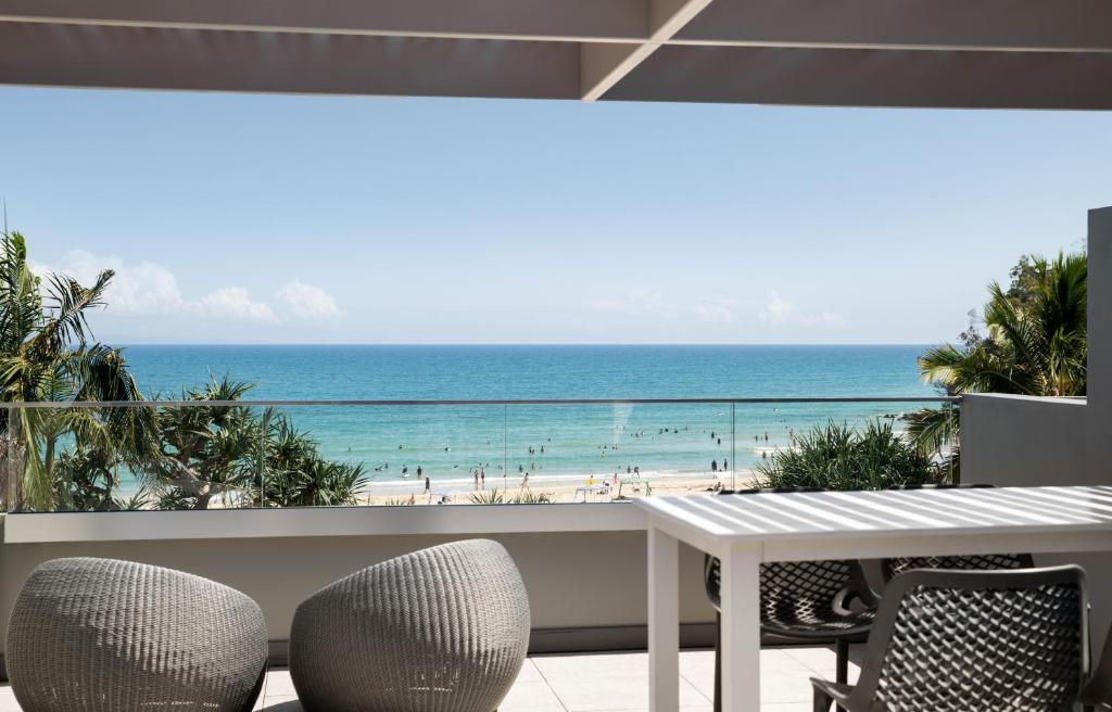 努萨角Netanya Noosa Beachfront Resort的一个带桌椅和海滩的阳台