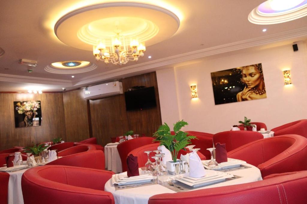 雅温得Matcheu palace Hôtel的餐厅设有红色的桌椅和吊灯