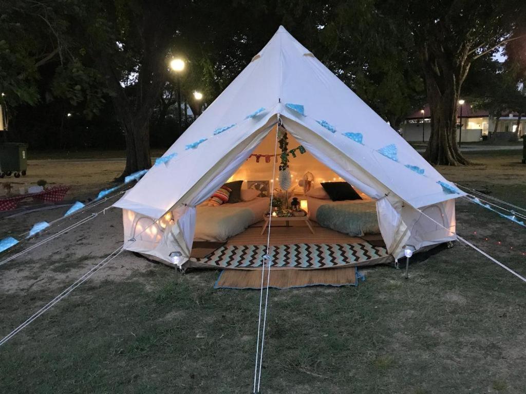 新加坡Glamping kaki singapore-Standard medium bell tent的夜晚在田野里的一个白色帐篷