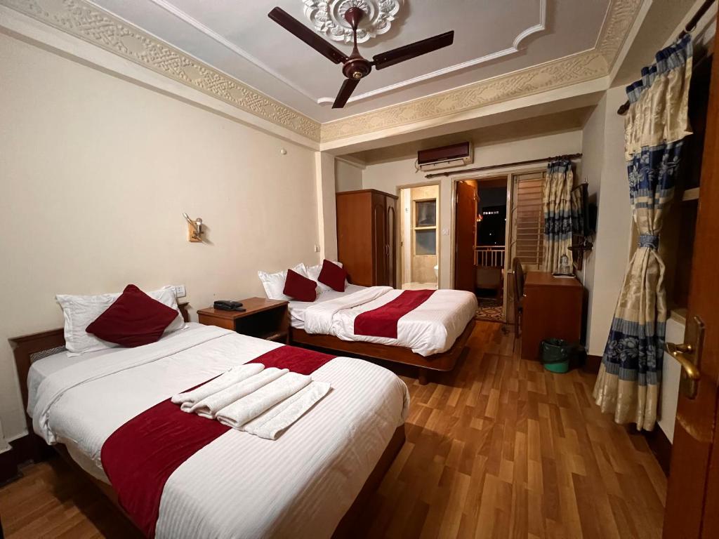 加德满都跋涉之家酒店的一间卧室配有两张红色和白色床单