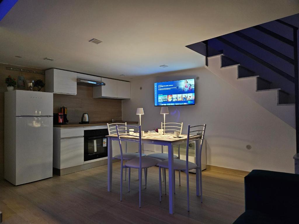 那不勒斯Casa savoia dream的厨房配有桌椅,墙上配有电视。