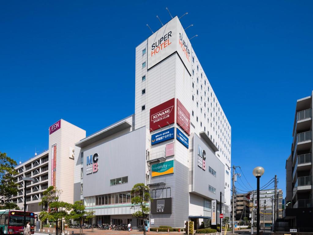 市川市Super Hotel Tozai line Ichikawa Myoden Ekimae的一座高大的白色建筑,有许多标志