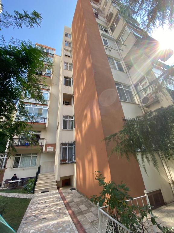 伊斯坦布尔Kadıköy Kozyatağında Kiralık Daire的一座高大的公寓楼,前面有一个人