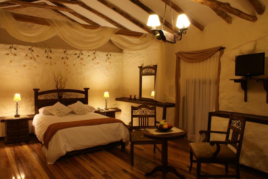 库斯科库斯科乌奈同姆布精品酒店的一间卧室配有一张床、一张桌子和一台电视。