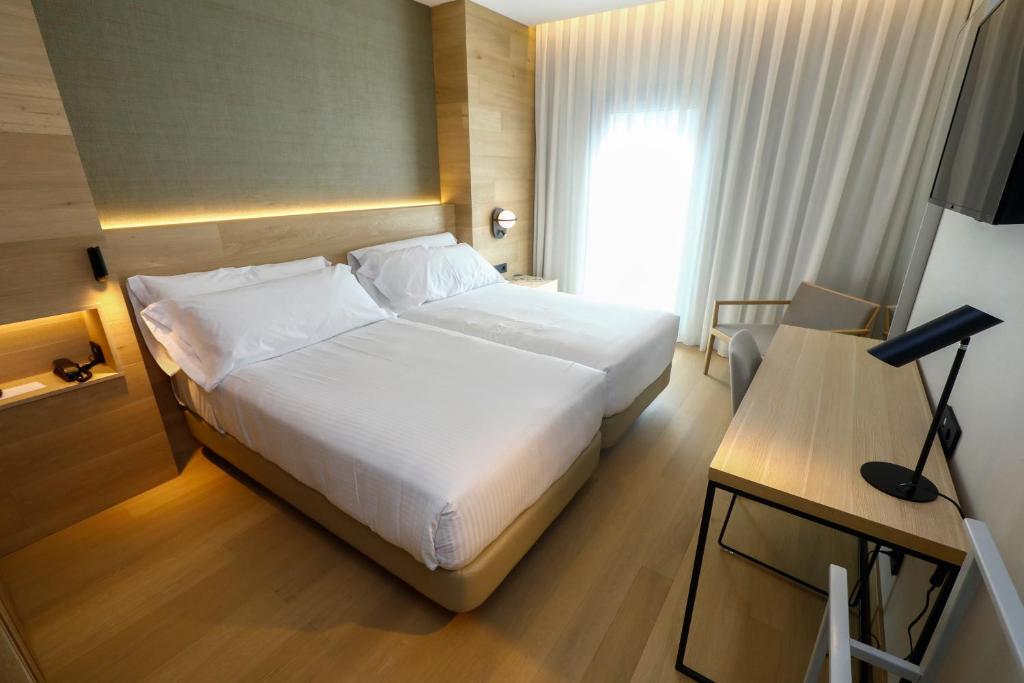 毕尔巴鄂泽尼特毕尔巴鄂酒店的卧室配有白色的床和带台灯的书桌