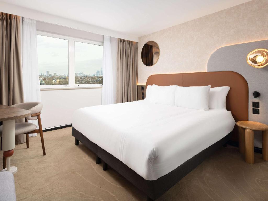 伦敦Mercure London Earls Court的酒店客房设有白色的床和窗户。