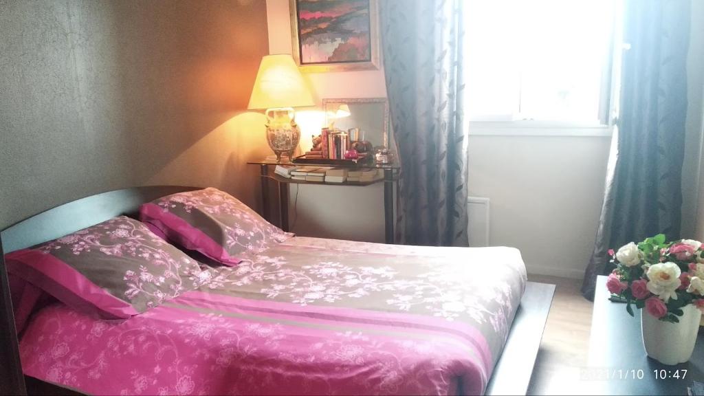 瑟堡Chambre Rafaël chez particulier的卧室配有粉红色的床和花瓶