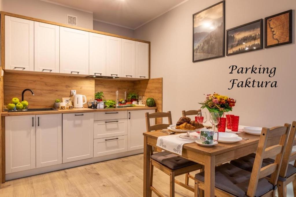下乌斯奇基Apartament Słoneczny Poranek的厨房配有白色橱柜和木桌